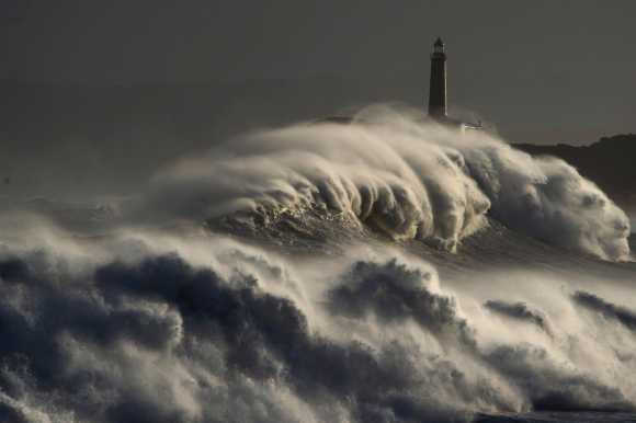 Una ola rompe en el faro de la isla de Mouro hoy domingo en la capital cántabra. /EFE
