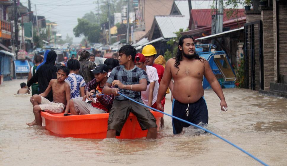 Varias personas a bordo de un bote durante una operación de rescate en la villa de Bulan, en Filipinas (EFE/EPA/ROMEDOR GLORIANE)