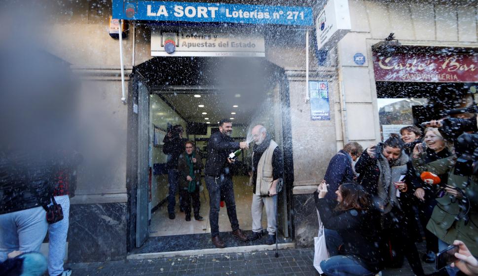 El dueño de la administración de lotería de la calle Travessera de Gràcia muestra su alegría tras haber vendido integramente el primer premio del sorteo de El Niño (EFE/Alejandro García)