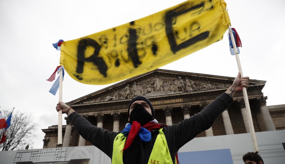 Un manifestante de los 'chalecos amarillos' sostiene una pancarta que reza 'RIC' (Referéndum de Iniciativa Ciudadana) EFE