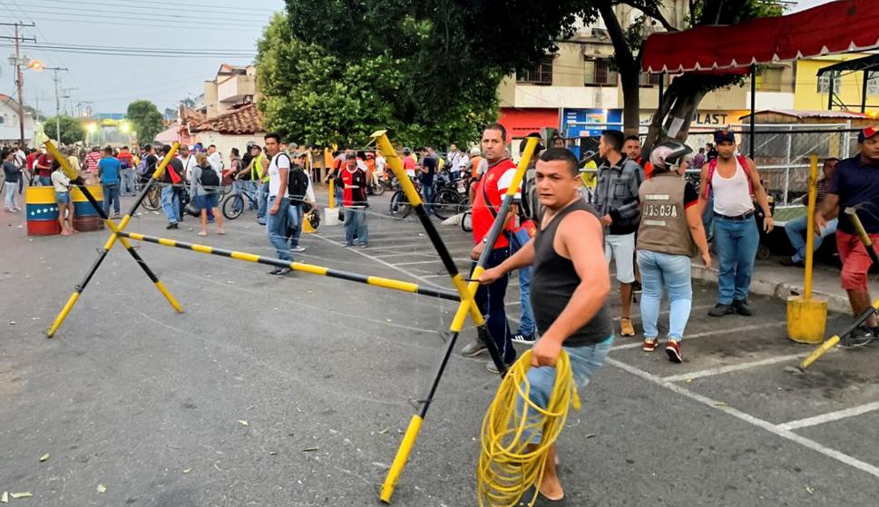 Un grupo de personas desarman las barreras de seguridad instaladas por la Guardia Nacional Bolivariana (GNB) que bloquean el paso sobre el río Táchira (EFE/HECTOR PEREIRA)