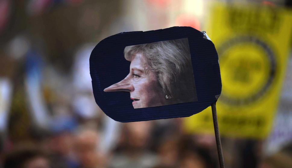 Un cartel que muestra una foto de la primera ministra británica, Theresa May, con la nariz de Pinocho, durante la marcha para exigir otro referéndum del Brexit (EFE/EPA/NEIL HALL)