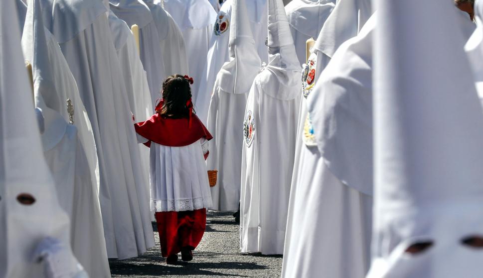 Una niña acompaña a los Nazarenos de la Paz en la estación de penitencia de su Hermandad, en la jornada en la que comienzan los desfiles procesionales del Domingo de Ramos en Sevilla. EFE/Jose Manuel Vidal