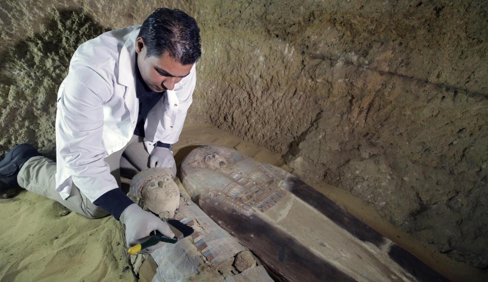 Un arqueólogo egipcio trabaja en un sarcófago en una d elas tumbas halladas en la meseta de Guiza./ EFE/EPA/KHALED ELFIQI