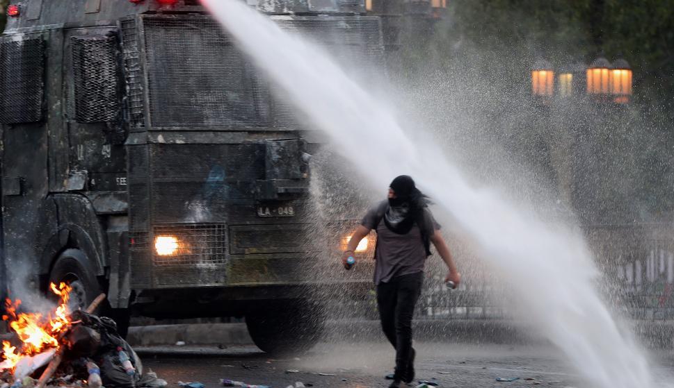 Un manifestante camina bajo el chorro de agua lanzado por la policía durante una nueva jornada de protestas. /EFE