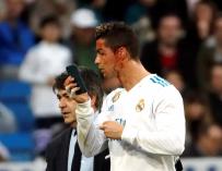 El delantero portugués del Real Madrid, Cristiano Ronaldo, se mira en un teléfono móvil tras ser golpeado en la cara durante el partido de la vigésima jornada de Liga que disputan esta tarde ante el Deportivo en el estadio Santiago Bernabéu de Madrid. EFE