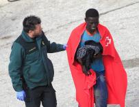 Un agente de la Guardia Civil ayuda a uno de los tres inmigrantes rescatados hoy por Salvamento Marítimo cuando viajaban en una patera en aguas del Estrecho y que han sido trasladados al puerto de Tarifa (Cádiz). EFE/A.Carrasco Ragel