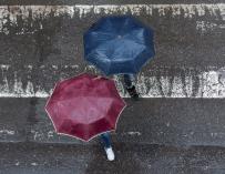 En la imagen, dos peatones cruzan por un paso de cebra, tapándose de la lluvia con su paraguas, en la ciudad gallega de Ourense. EFE/Brais Lorenzo