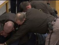 Captura de vídeo del momento en el que el padre de las víctimas es retenido por los agentes