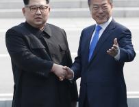 Moon Jae-in (d) y Kim Jong-un (i) se dan la mano en la línea de demarcación militar (MDL)
