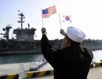 Un marinero de la República de Corea (ROK) ondea banderas al paso del portaaviones de la clase Nimitz USS Carl Vinson (Foto: MC2 Jermaine M. Ralliford)