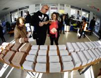 Los primeros votantes del colegio público Pinar del Rey de Madrid recogen papeletas electorales para ejercer su derecho al voto. /EFE/Javier Lizón