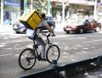 Trabajador de la empresa Glovo montando en bicicleta por Madrid