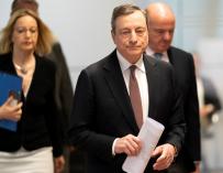 Draghi camina hacia la rueda de prensa escoltado por Guindos.