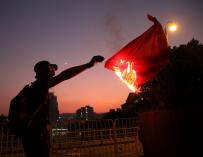 Un ciudadano quema una bandera de China. / EFE