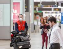Un operario con mascarilla traslada maletas en el aeropuerto de Barajas, casi vacío