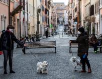 Fotografía de dos personas paseando al perro en Roma durante la crisis del coronavirus.