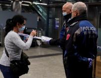 Policías entregan una mascarilla a una mujer en la estación de metro de Nuevos Ministerios en Madrid, este lunes. Según anunció el pasado sábado el ministro de Sanidad, Salvador Illa, las fuerzas de seguridad repartirán 10 millones de mascarillas este lun