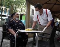 Un camarero limpia la mesa antes de atender en una terraza de Córdoba durante la Fase 1