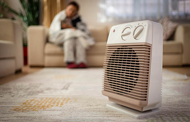 A young man heats the living room with a heater